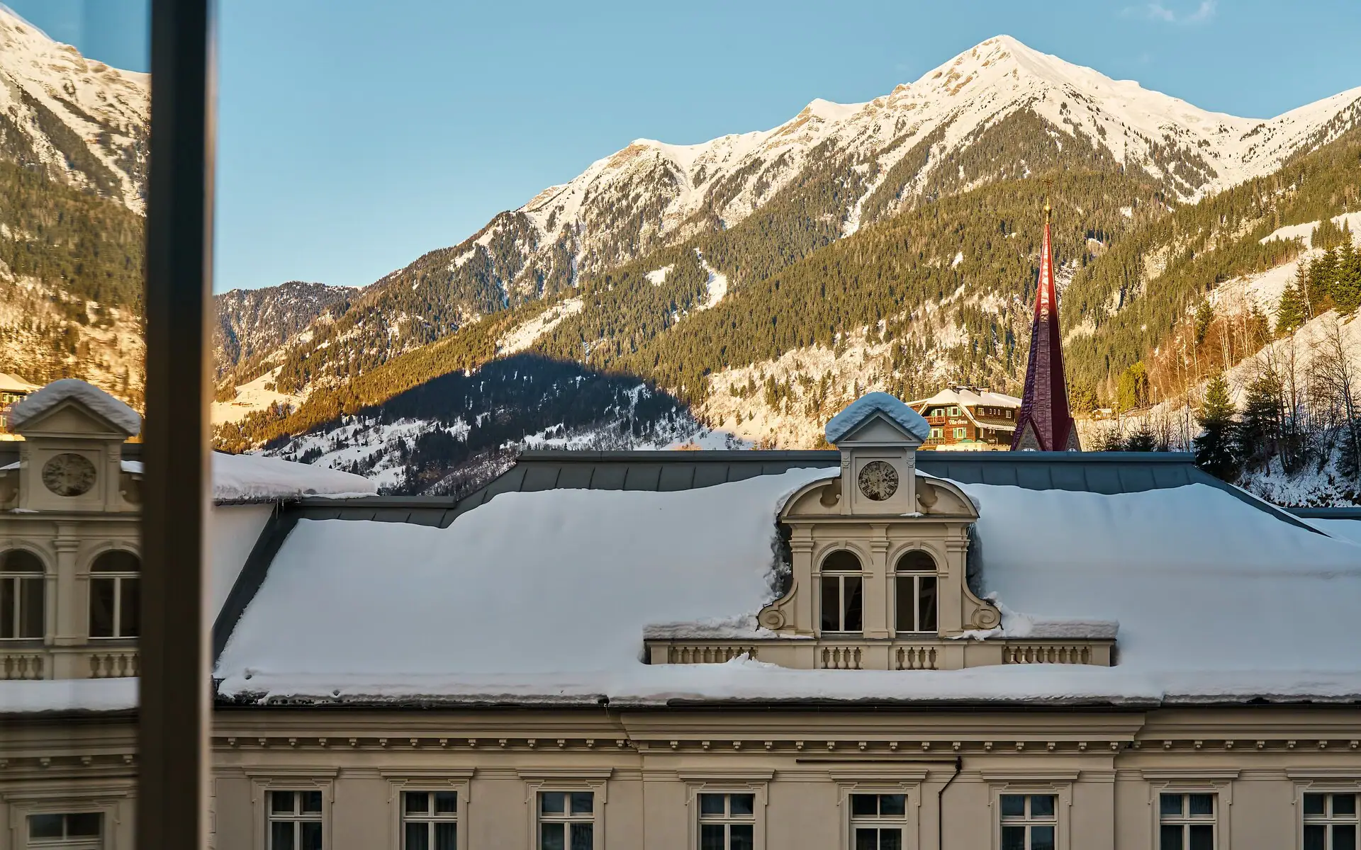 Outlook A building with snow on the roof and mountains in the background.