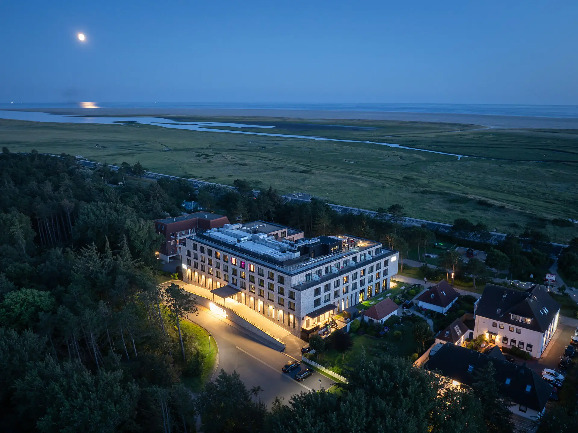 Urban Nature St Peter-Ording An illuminated building and a road in the middle of a field at night.