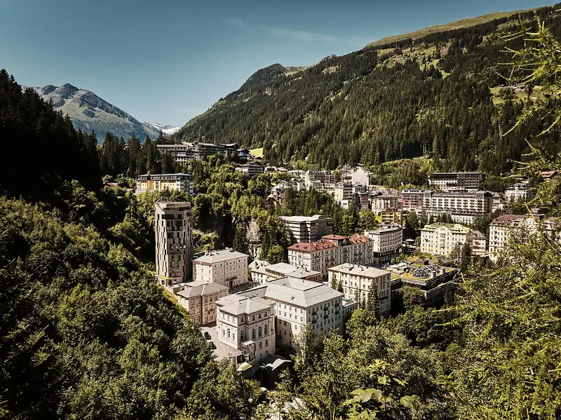 Urban Nature Bad Gastein Eine Stadt in den Bergen mit Häusern und Bäumen unter einem bewölkten Himmel.