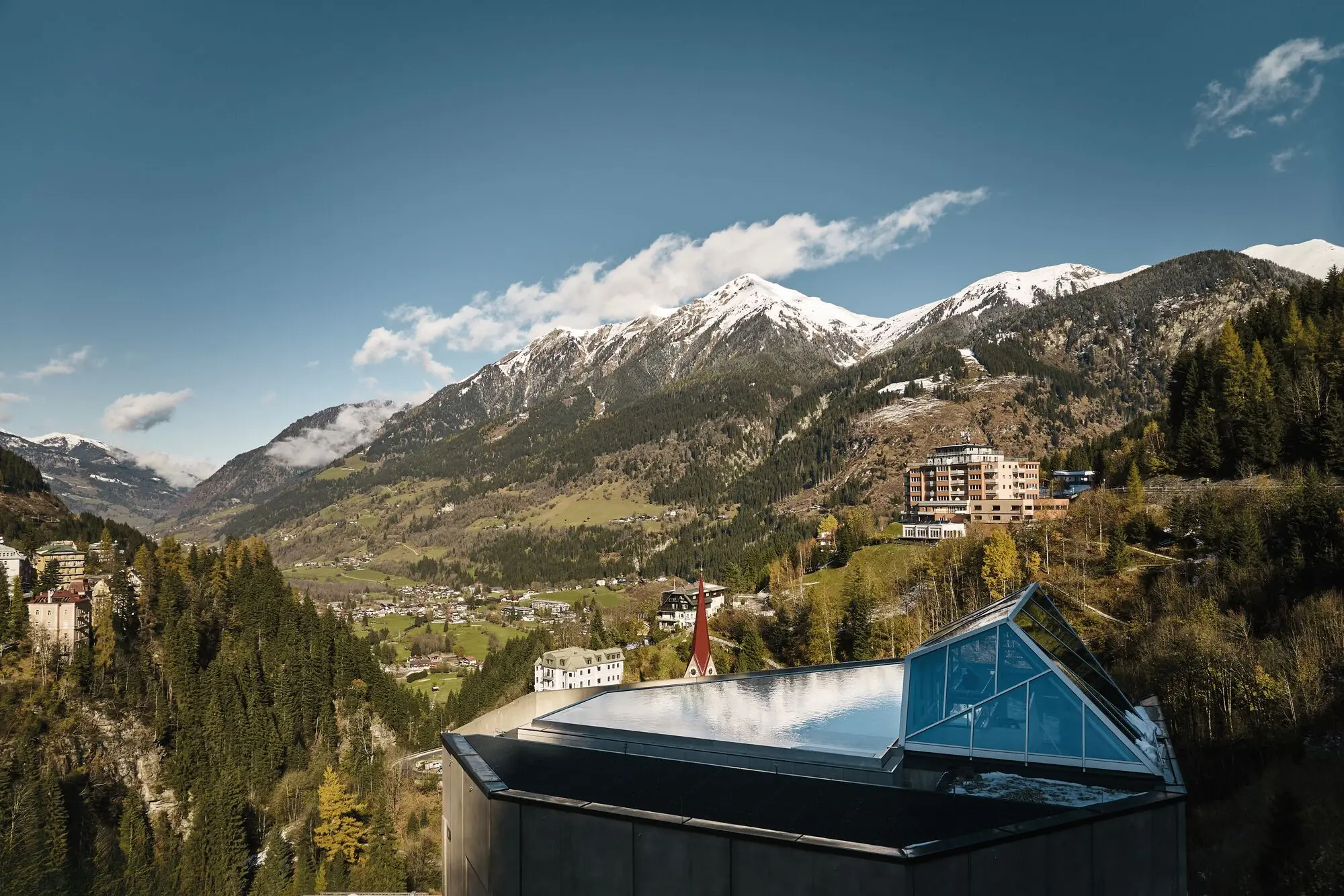 Urban Nature Bad Gastein A building with a glass roof set against a mountain range.