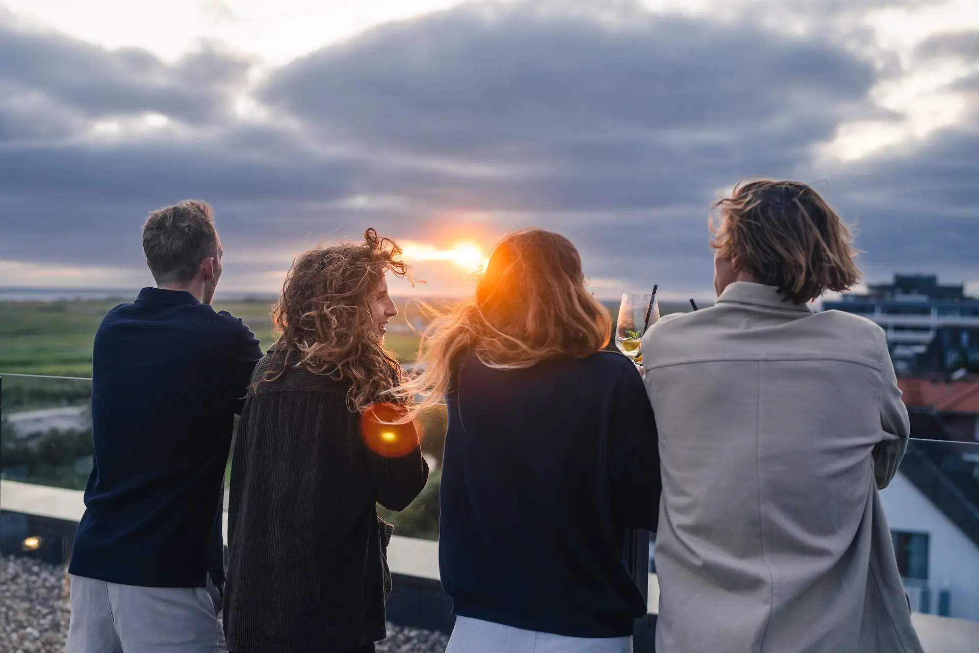 Sunset A group of people are standing outside with drinks.