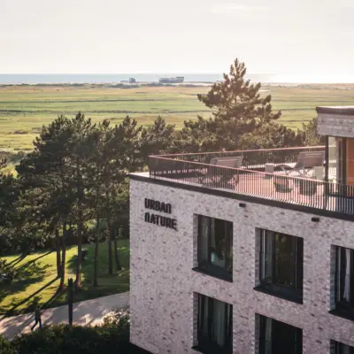 A building with a balcony overlooking a grassy field.